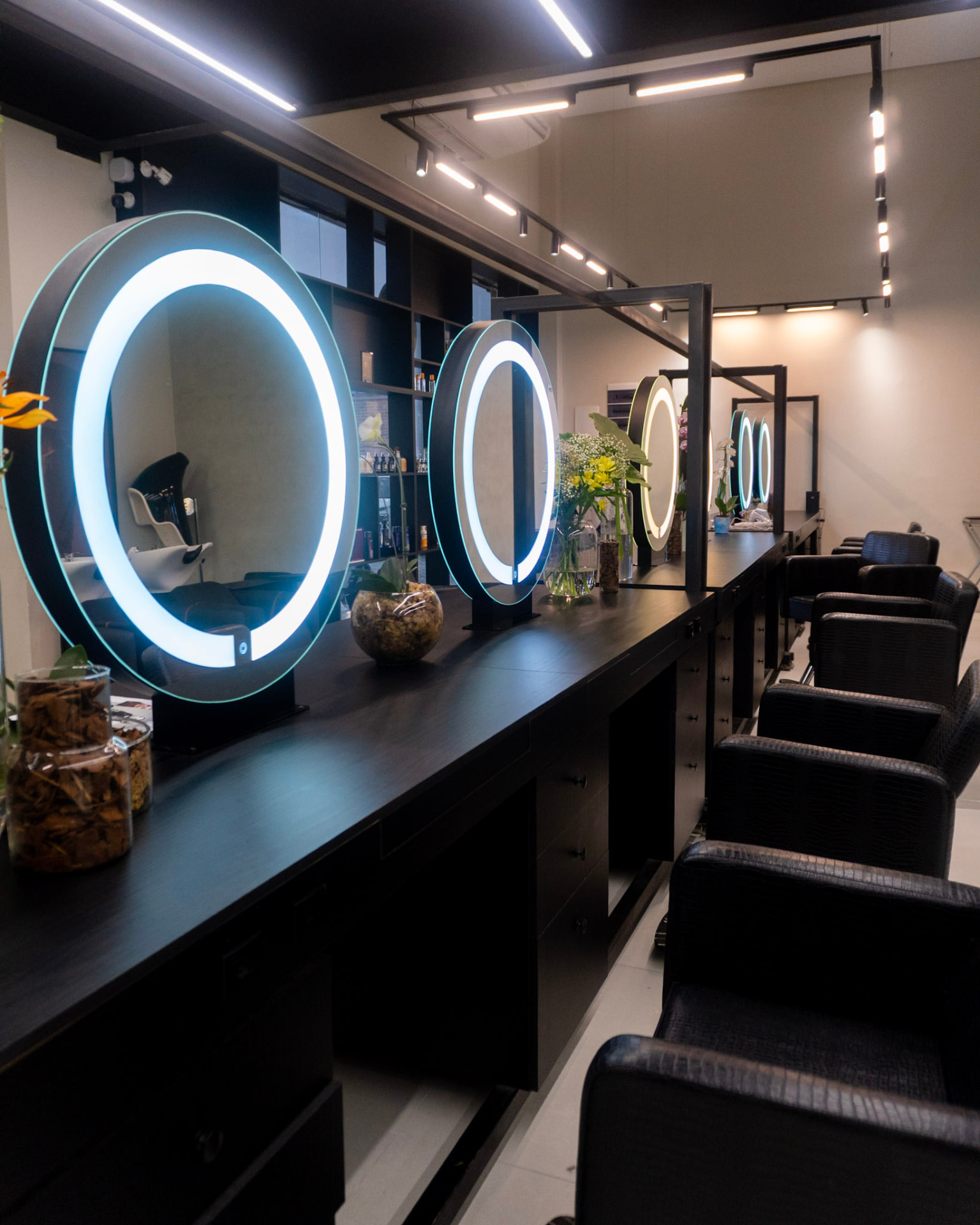 Salão da Casa Lagioia com bancada preta e espelhos redondos iluminados