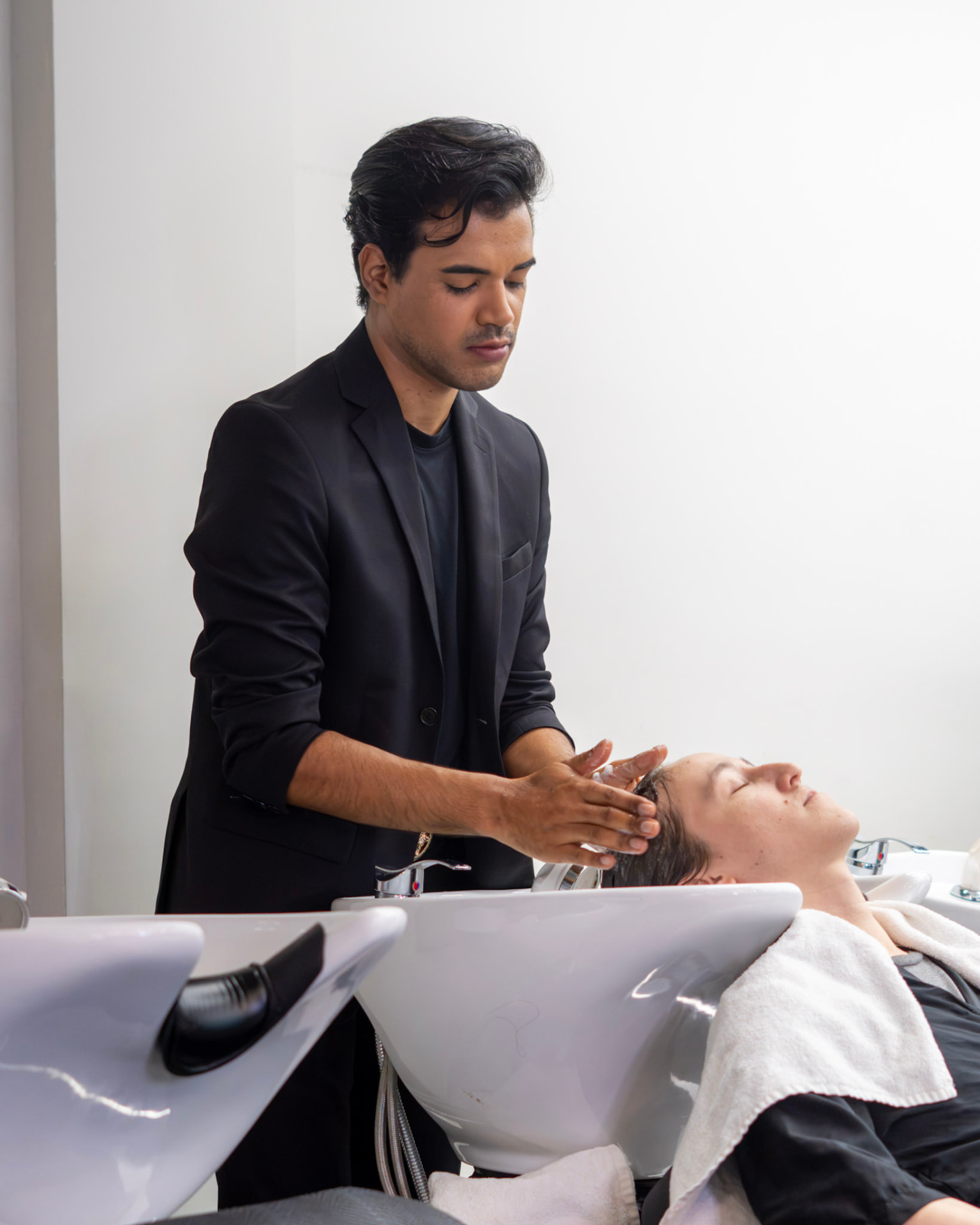 Profissional lavando o cabelo de uma cliente no lavatório